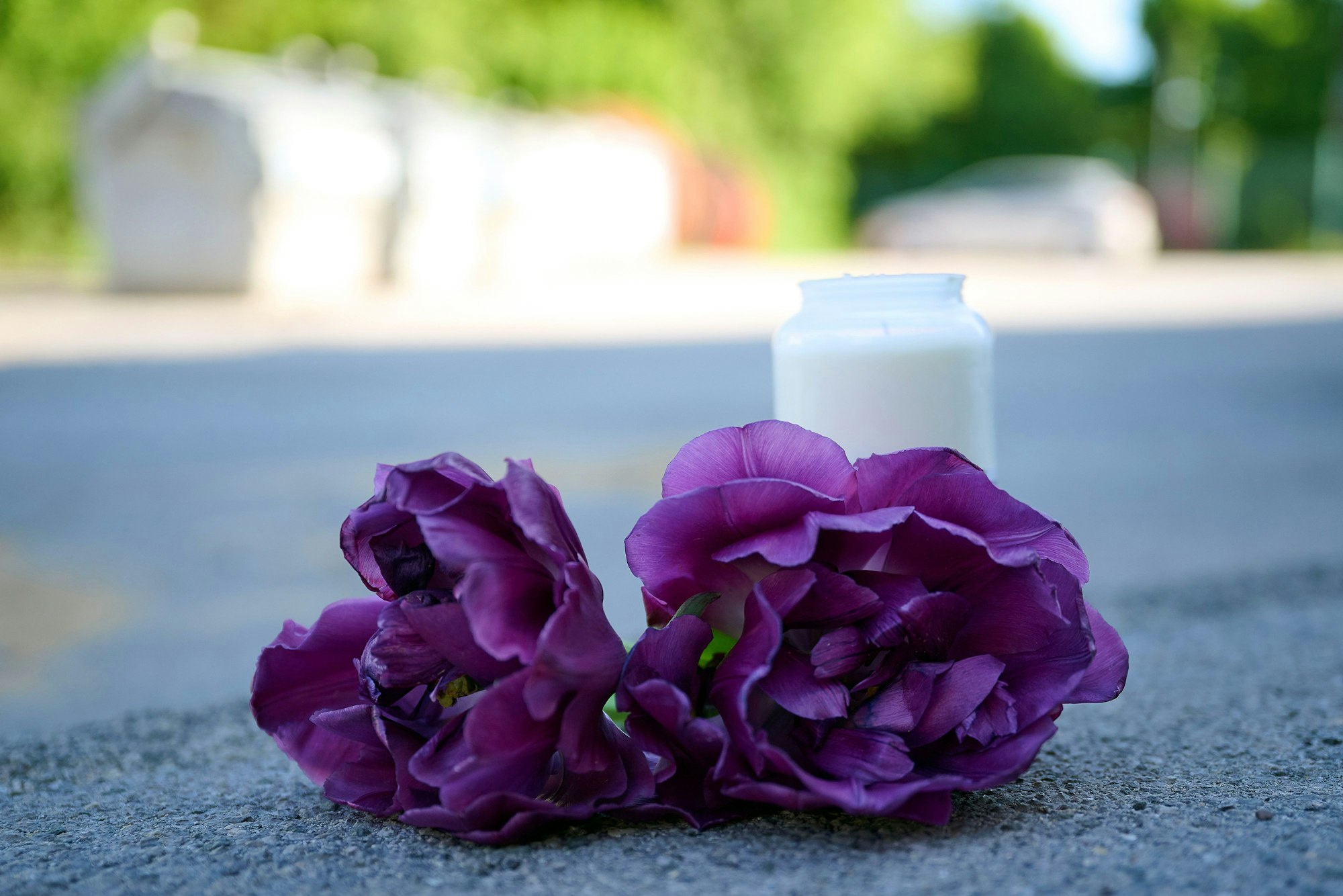 Blumen und eine Kerze liegen auf einem Schotterplatz vor dem Eingang zu einem Spielplatz.