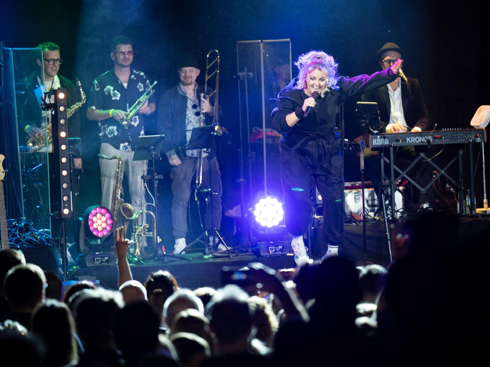 Die Musikband Kempes Feinest beim Konzert im Gloria. Nici Kempermann springt und hüpft.