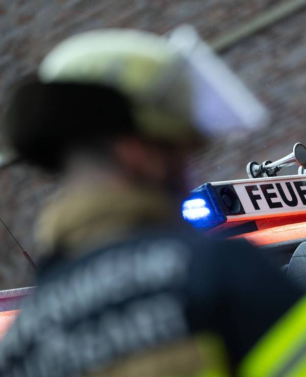 Eine Einsatzkraft der Feuerwehr steht vor einem Einsatzfahrzeug (gestellte Szene).