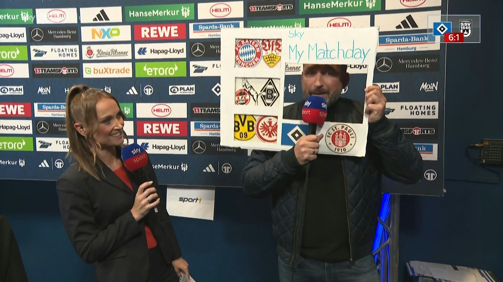 Torsten Mattuschka stellt mit einer Papptafel das neue Sky-Format „My Matchday“ vor. Moderatorin Nele Ocik steht daneben.