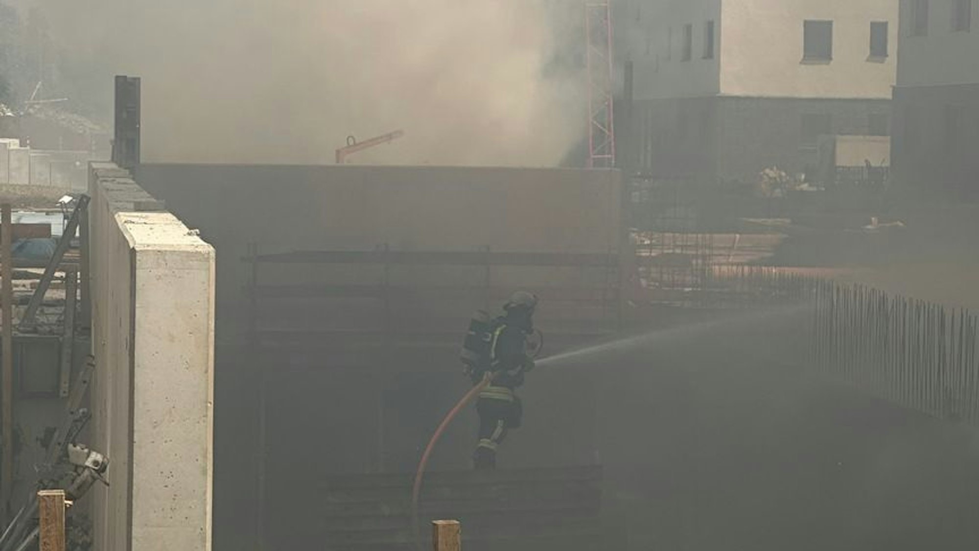 Ein Feuerwehrmann bekämpft den Brand auf der Tiefgaragenbaustelle in der östlichen Innenstadt von Dortmund