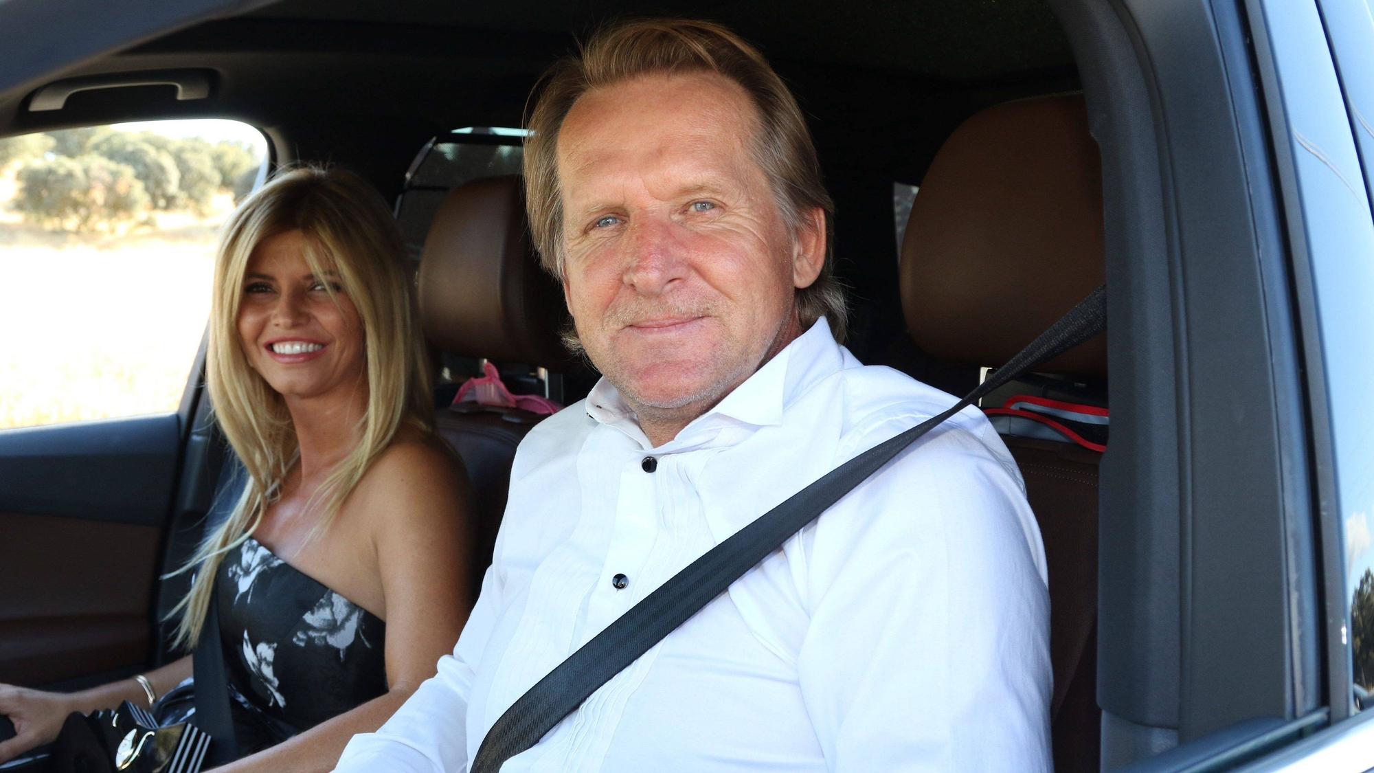 Bernd Schuster sitzt im Auto neben seiner Ehefrau, beide gucken lächelnd in die Kamera.