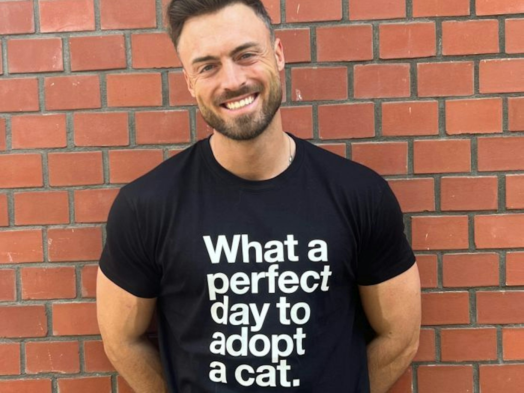 Ein Mann trägt ein T-Shirt mit der Aufschrift „What a perfect day to adopt a cat“.