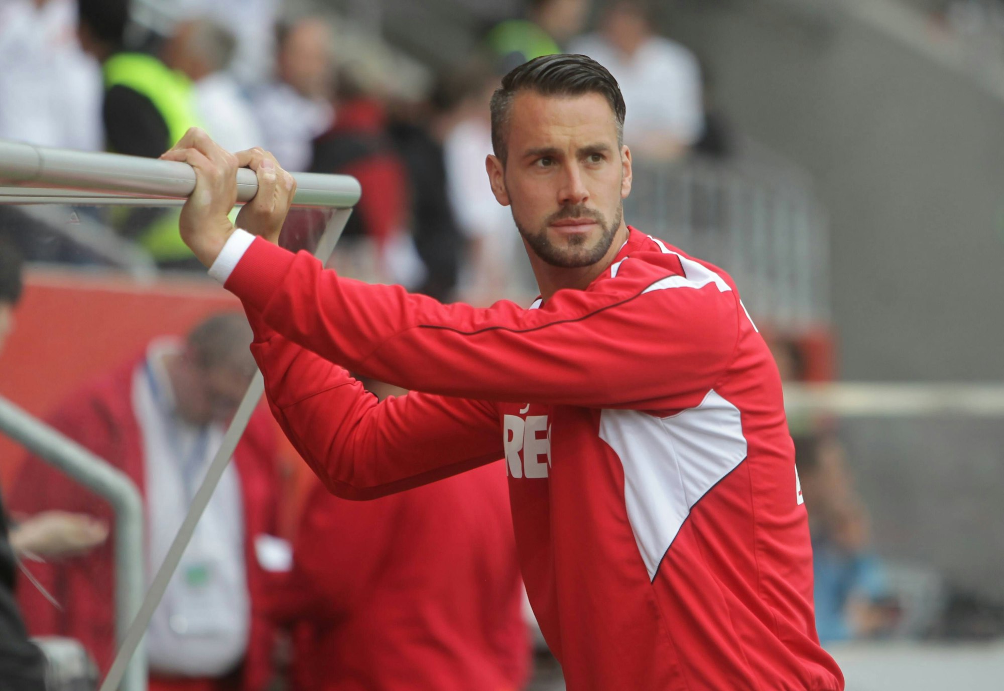 Stefan Maierhofer steht vor der Ersatzbank und stützt sich an der Überdachung ab.