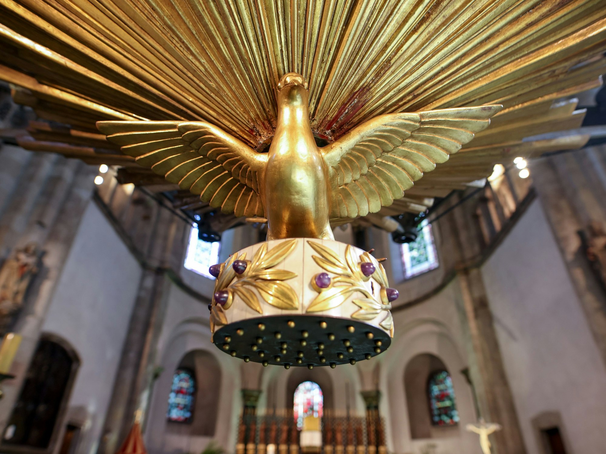 Eine vergoldete Taube hängt in einer Kirche.