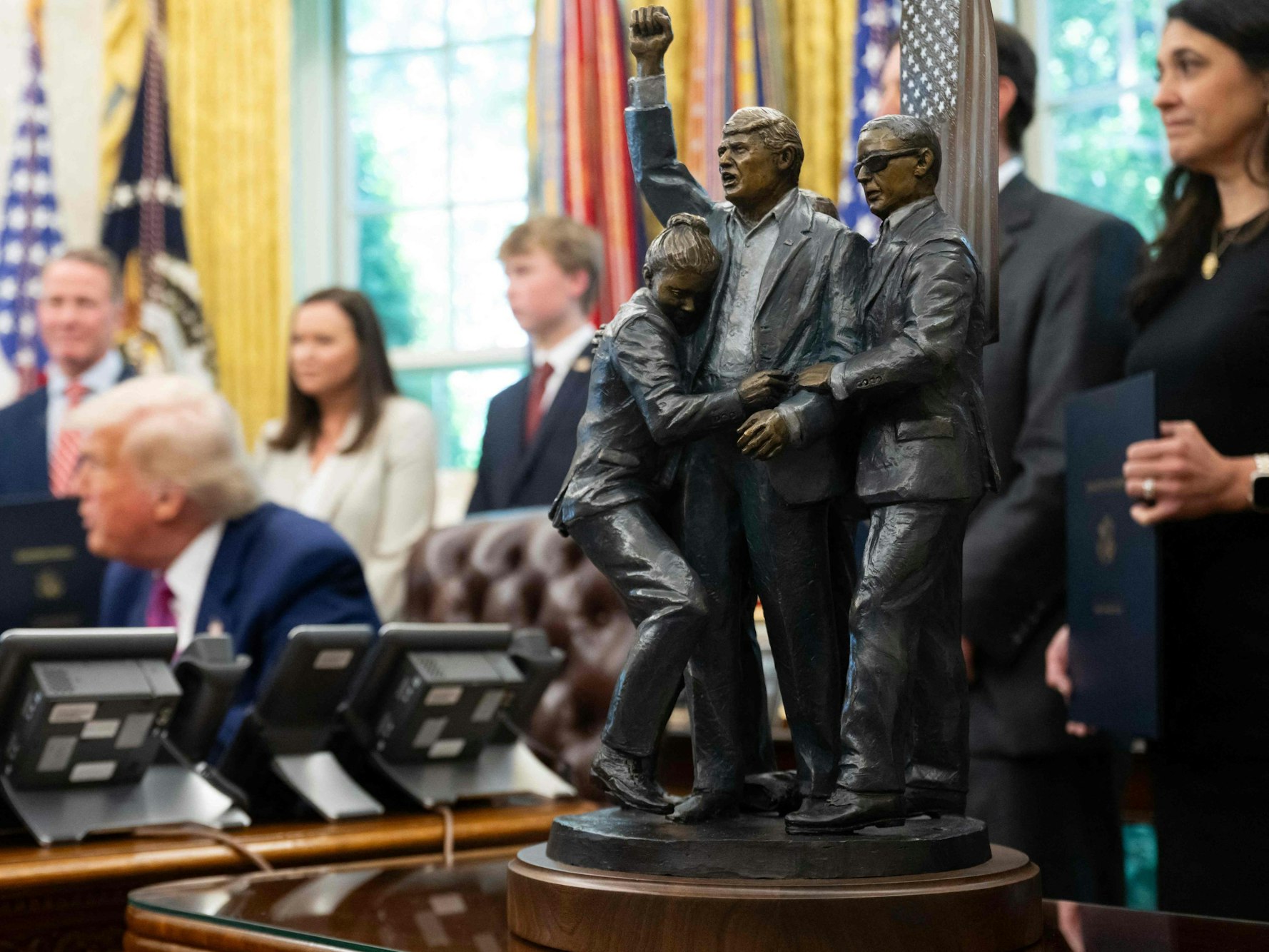 A statue depicting the attempted assassination of US President Donald Trump in Butler, Pennsylvania, sits alongside the Resolute Desk as Trump signs legislation relating to household consumer energy policies in the Oval Office of the White House in Washington, DC, on May 9, 2025. (Photo by SAUL LOEB / AFP)