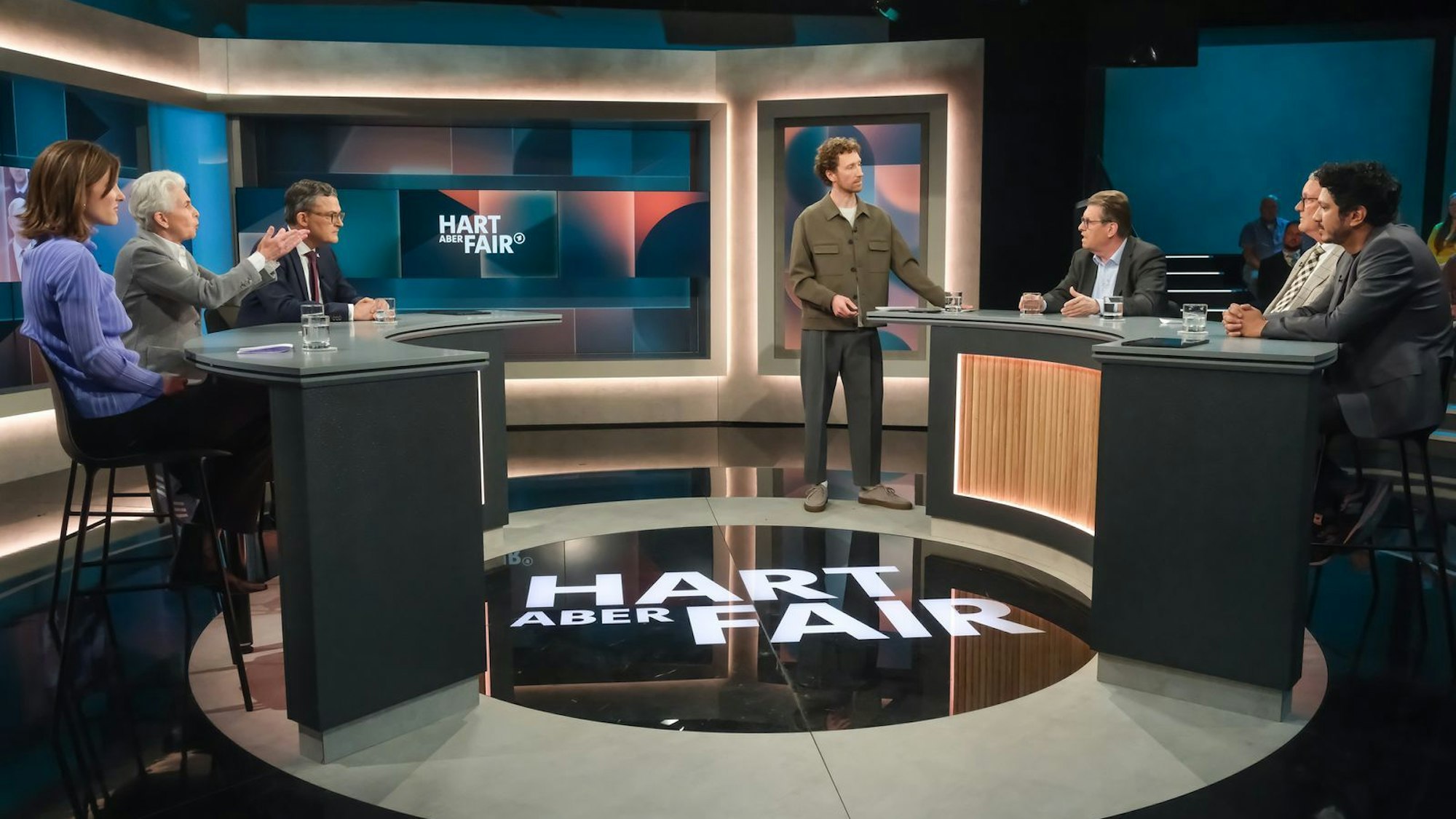 „Hart aber fair“ am Montagabend: Moderator Louis Klamroth (stehend) begrüßte seine Gäste (von links nach rechts) Sophie von der Tann, Marie-Agnes Strack-Zimmermann, Roderich Kiesewetter, Ralf Stegner, Michael Lüders und Jörg Wimalasena. (Bild: WDR/Oliver Ziebe)