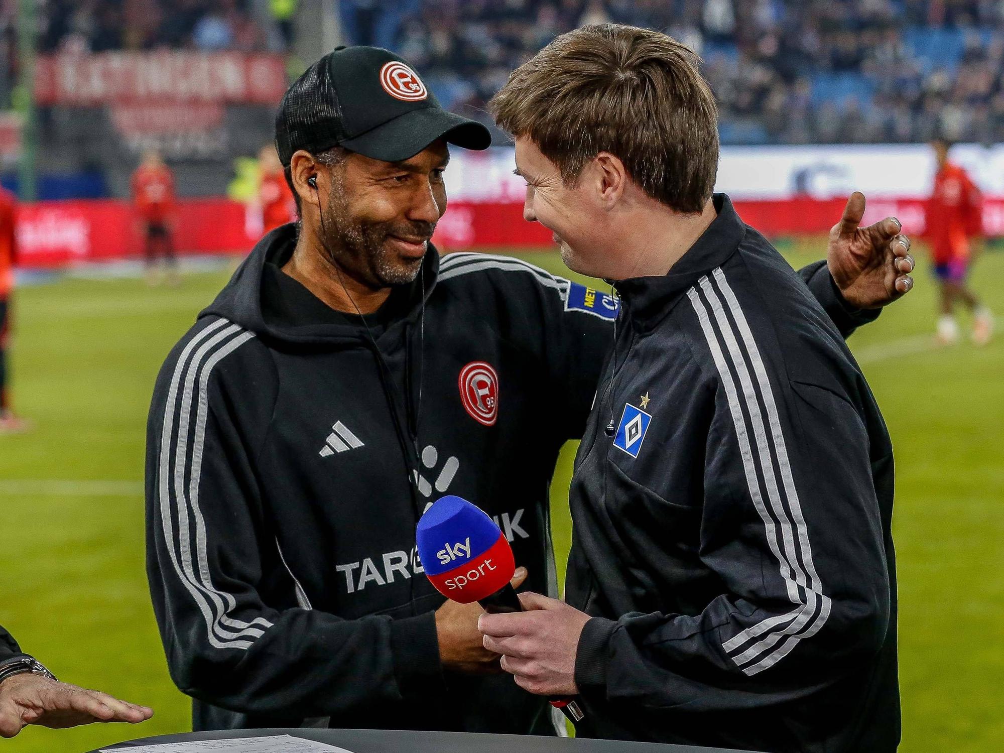 Merlin Polzin begrüßt seinen Freund und Kollegen Daniel Thioune bei einem TV-Interview am Spielfeldrand.