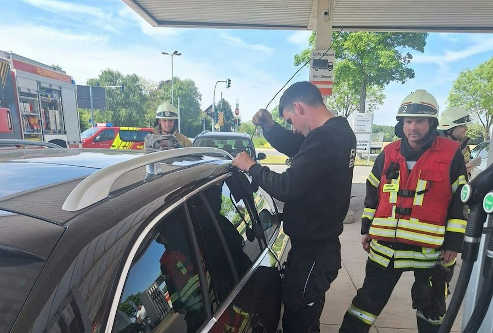 Einsatzkräfte der Feuerwehr Kalkar und ein KFZ-Meister bei der Rettung eines Kleinkinds aus einem verschlossenen Auto an einer Tankstelle in Appeldorn