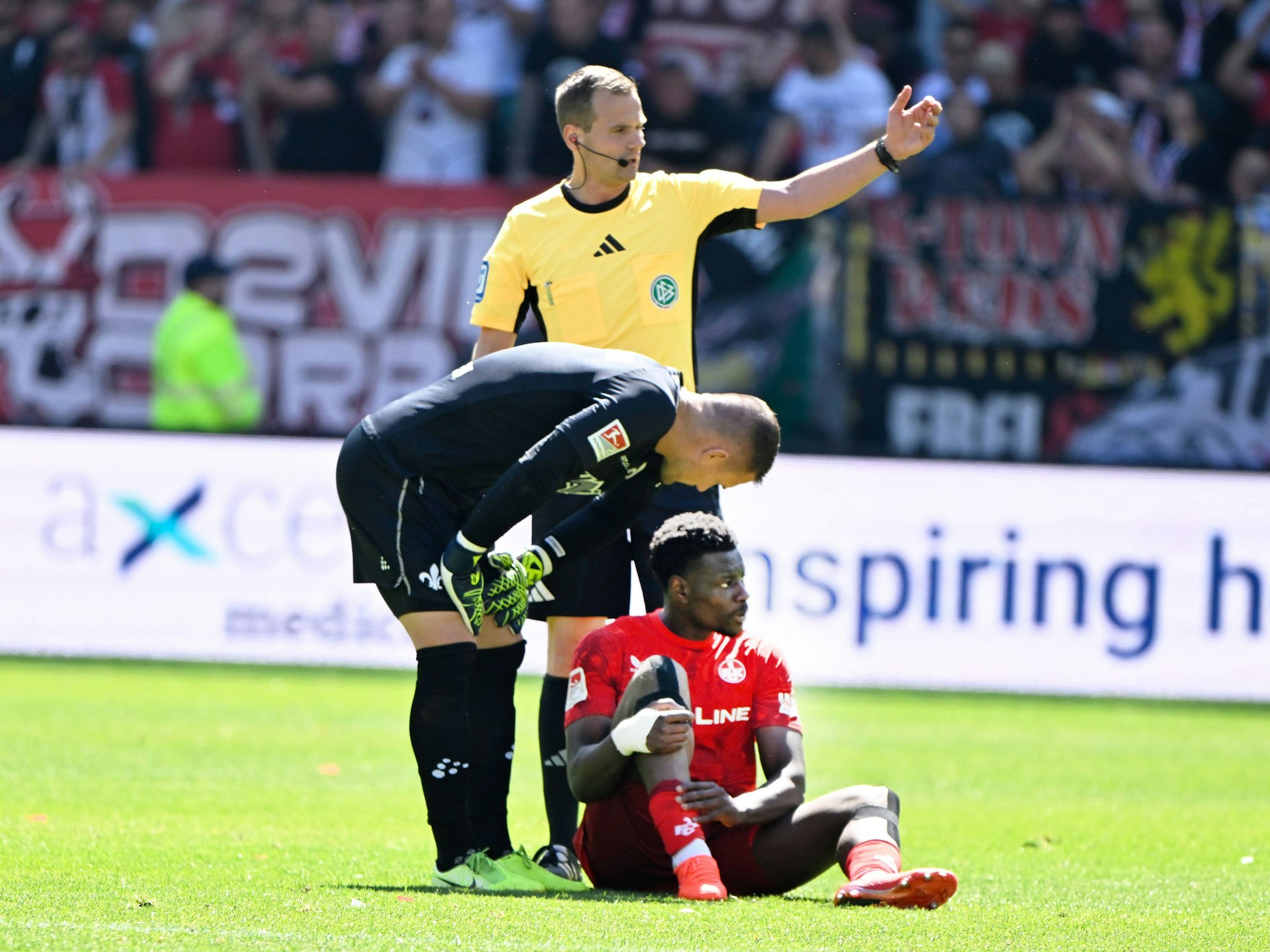 Ragnar Ache sitzt angeschlagen auf dem Rasen und hält sich das Bein.