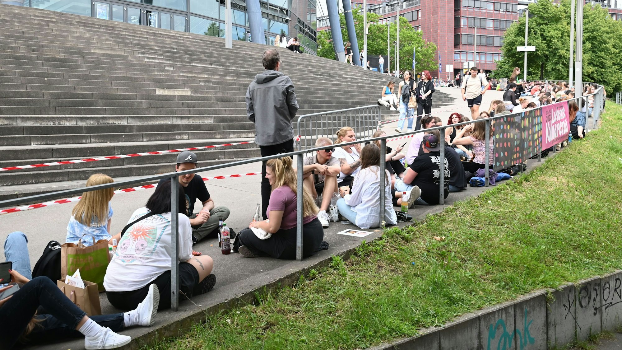 Fans warten vor der Lanxess Arena auf Einlass.