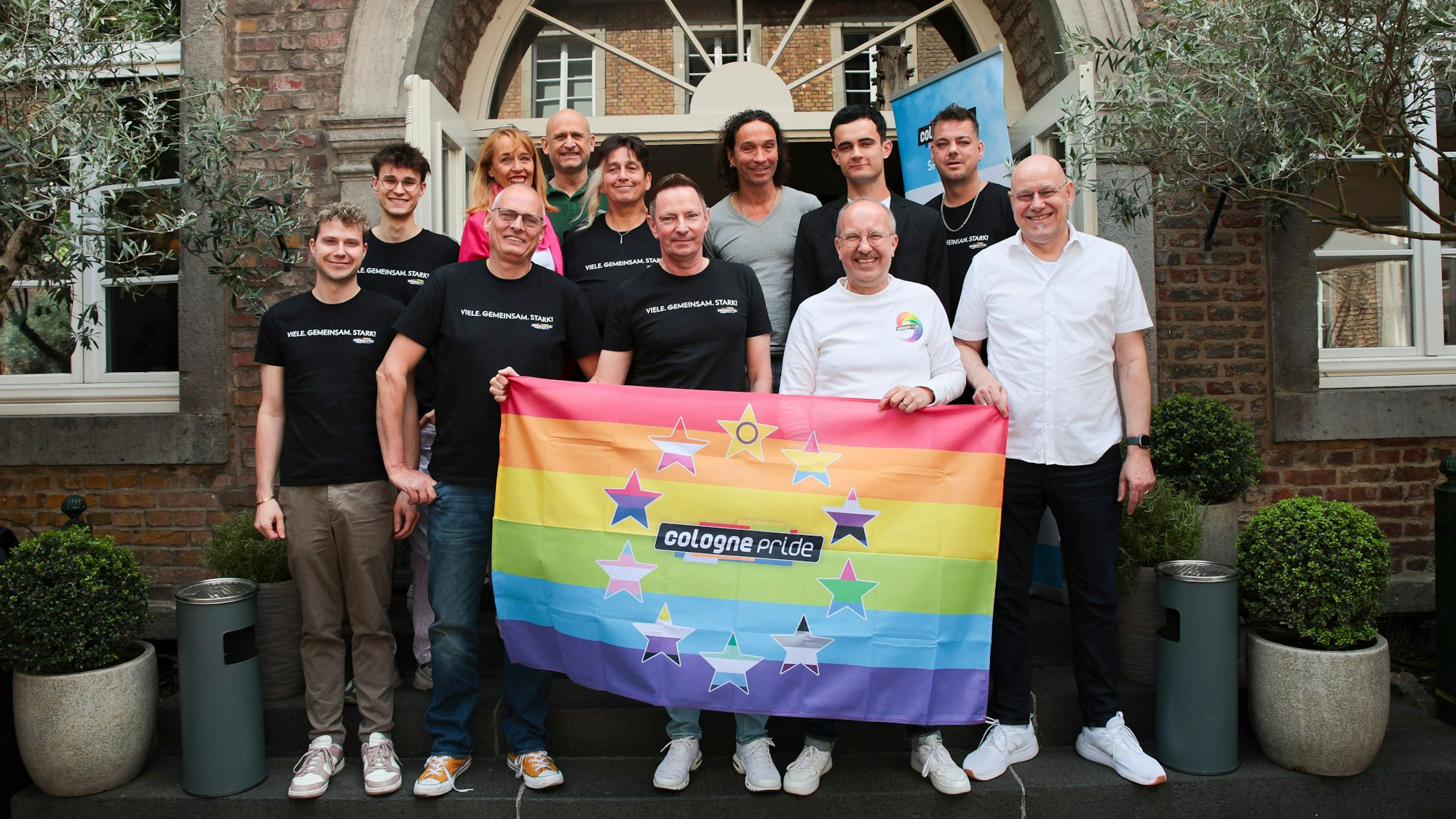 Team von ColognePride mit Fahne in der Hand.