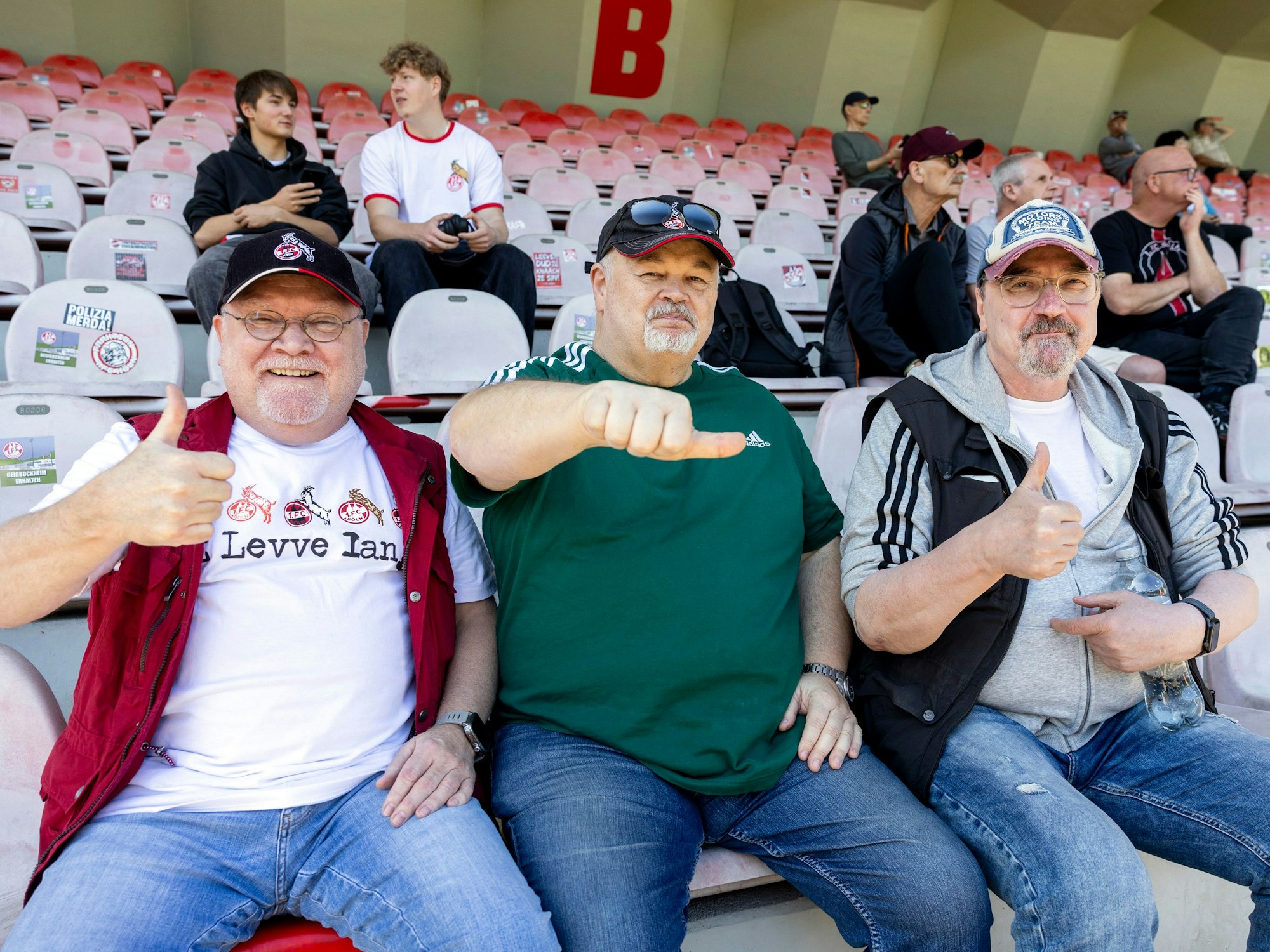 Fans sitzen auf einer Tribüne.