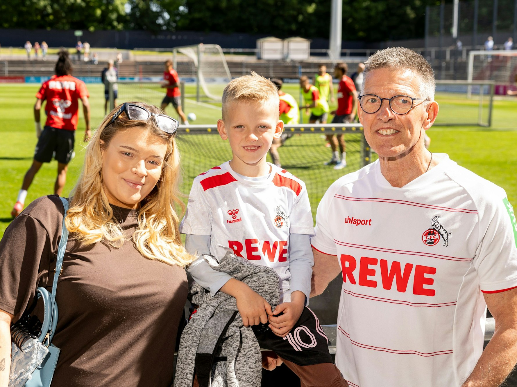 Fans stehen an einem Fußballfeld.