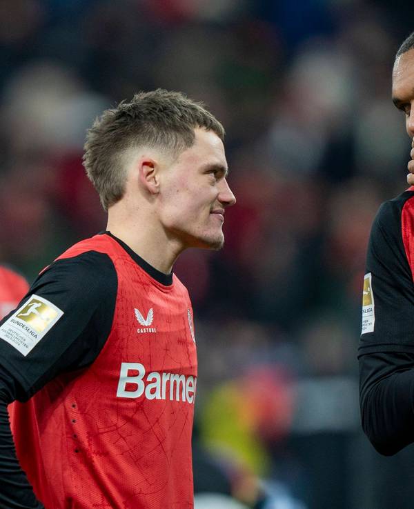 Jonathan Tah und Florian Wirtz von Bayer Leverkusen im Gespräch auf dem Platz.