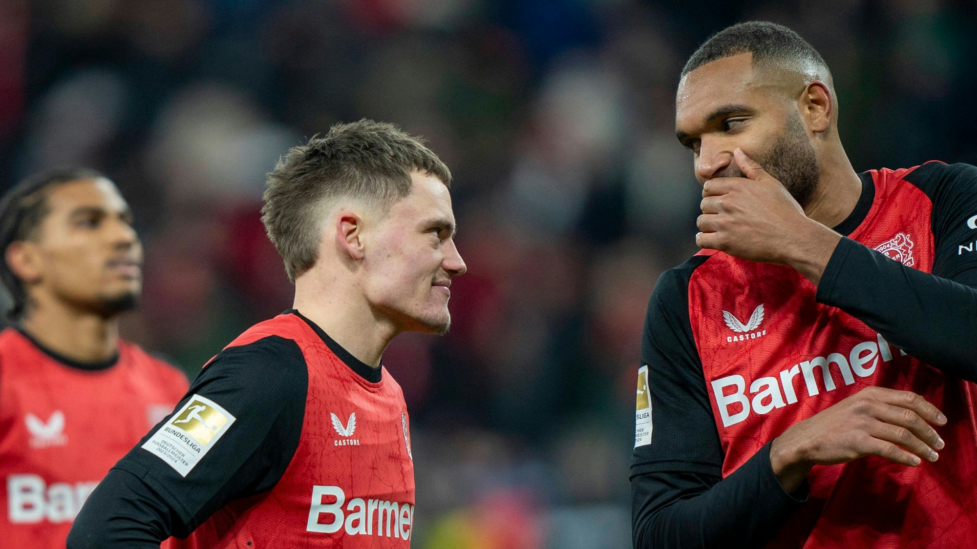 Jonathan Tah und Florian Wirtz von Bayer Leverkusen im Gespräch auf dem Platz.