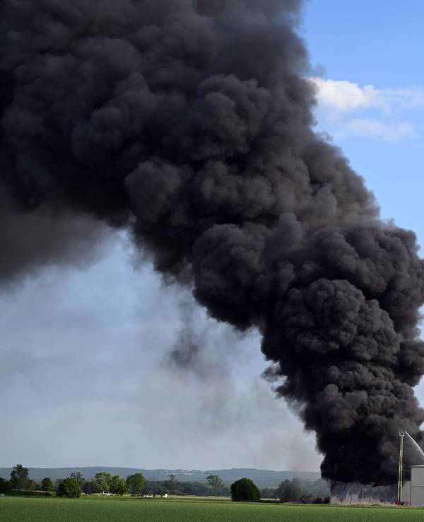 Eine riesige Rauchwolke ist beim Brand einer Lagerhalle mit Müll zu sehen.