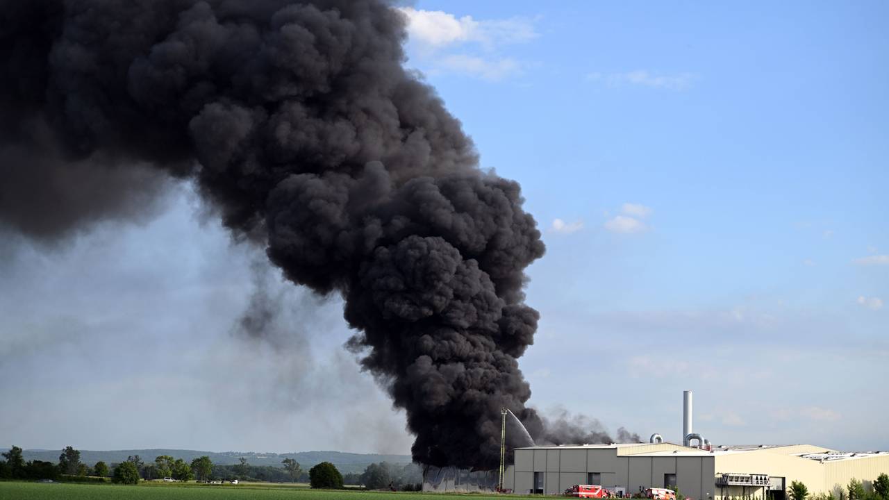 Eine riesige Rauchwolke ist beim Brand einer Lagerhalle mit Müll zu sehen.
