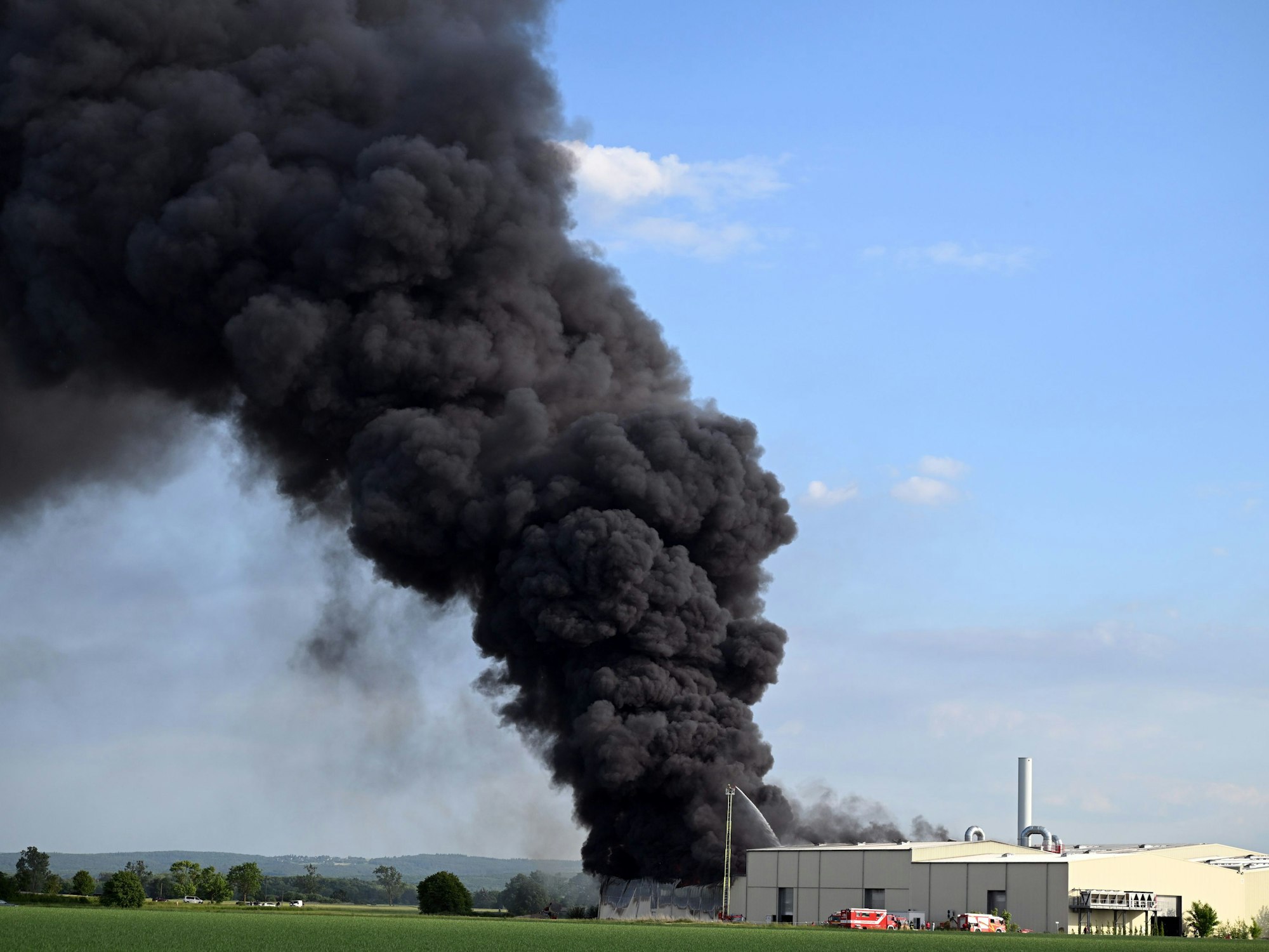 Eine riesige Rauchwolke ist beim Brand einer Lagerhalle mit Müll zu sehen.