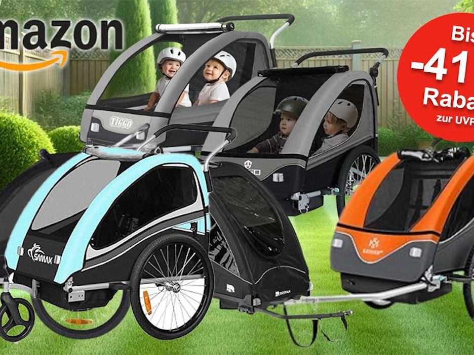 Kinder Fahrradanhänger verschiedener Marken vor einem grünen Garten im Hintergrund.