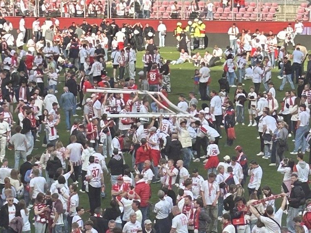 FC-Fans tragen ein Tor über den Rasen.