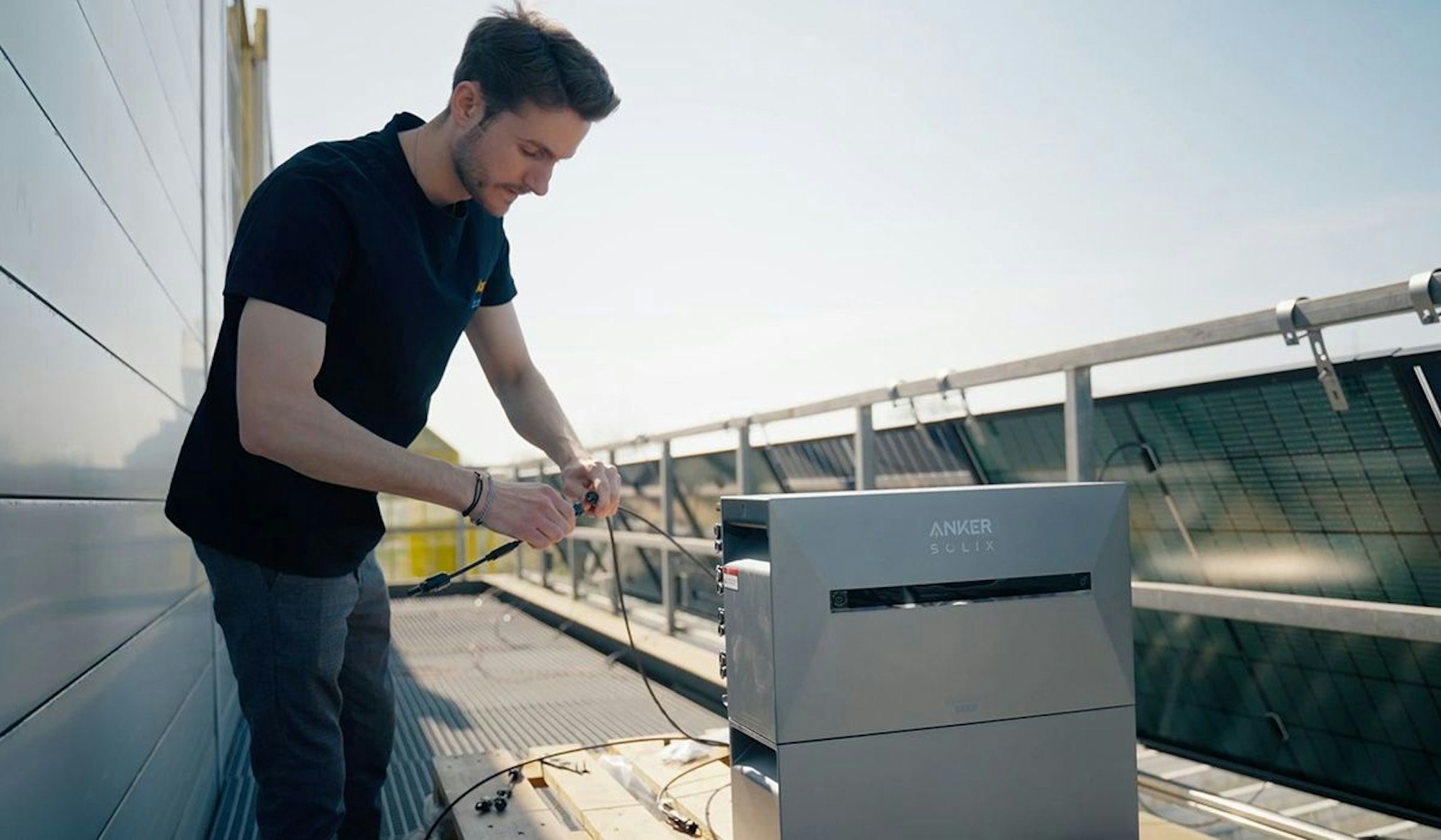 Ein Solago Mitarbeiter installiert eine Anker Solix 3 Pro Solar-Speicherbank an Balkonkraftwerk Solarpanelen.