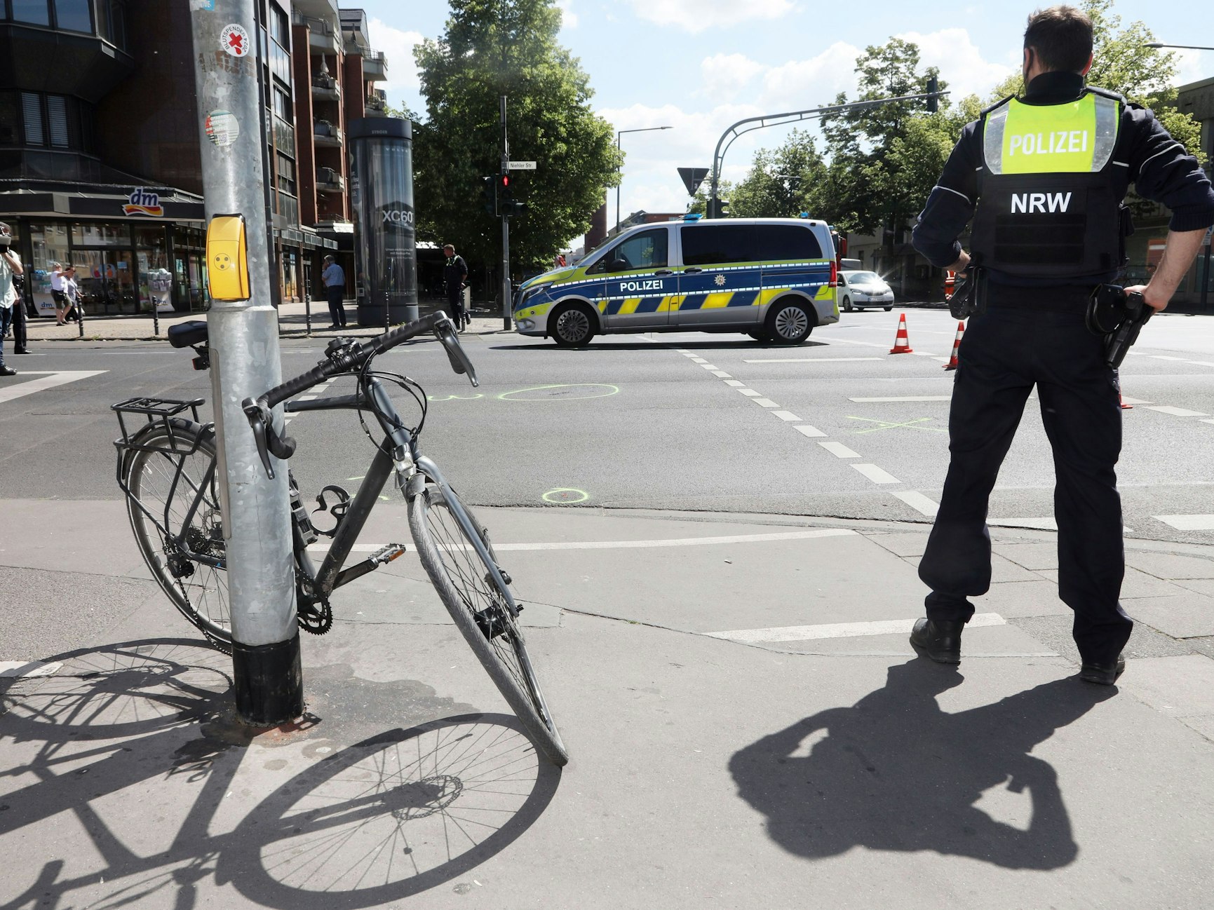 Ein Polizist steht neben einem Fahrrad, das an eine Ampel angelehnt ist.