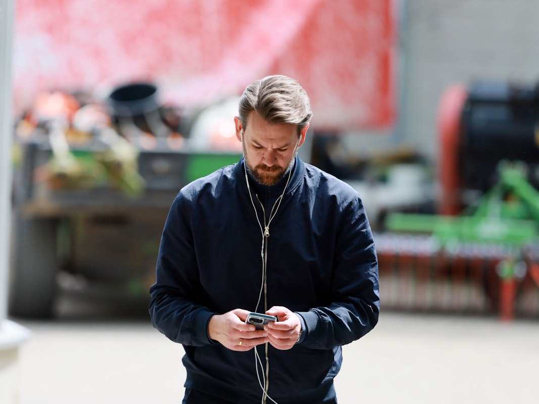 Thomas Kessler hat Kopfhörer in den Ohren und schaut auf sein Handy.