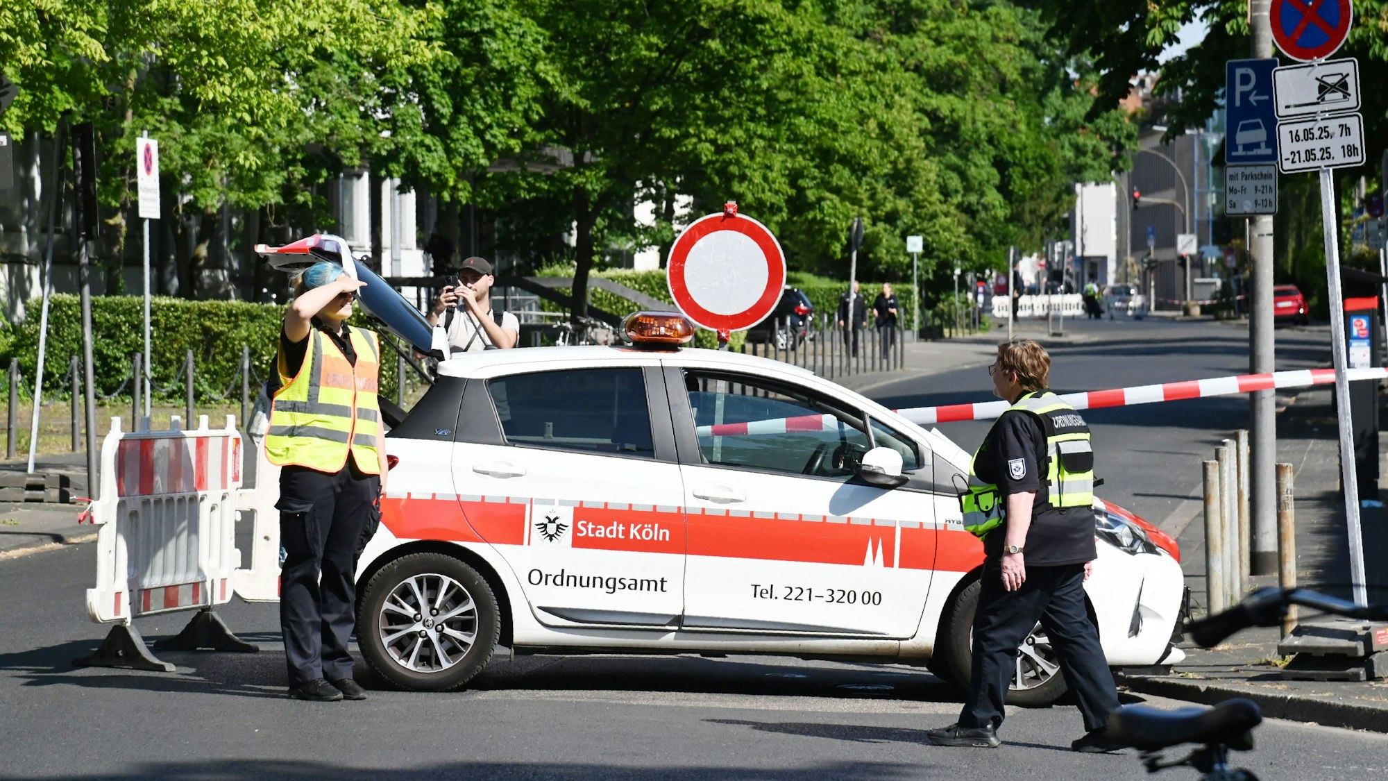 Eine Straße ist gesperrt, davor stehen ein Fahrzeug des Ordnungsamtes sowie zwei Mitarbeitende.