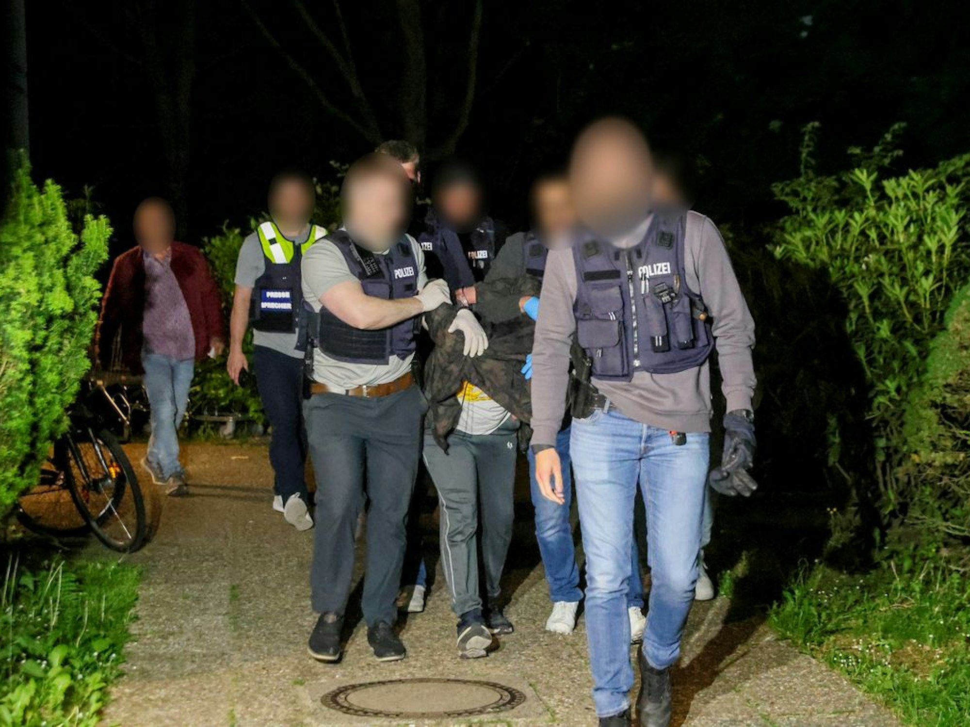 Einsatzkräfte der Polizei führen einen Tatverdächtigen nach seiner Festnahme in Heiligenhaus ab.