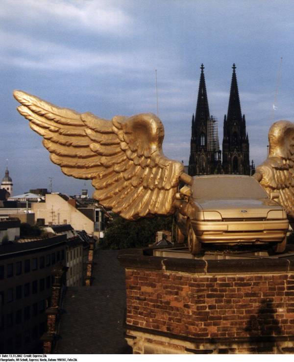 Ein goldenes Autos mit Flügeln steht auf einem Turm.