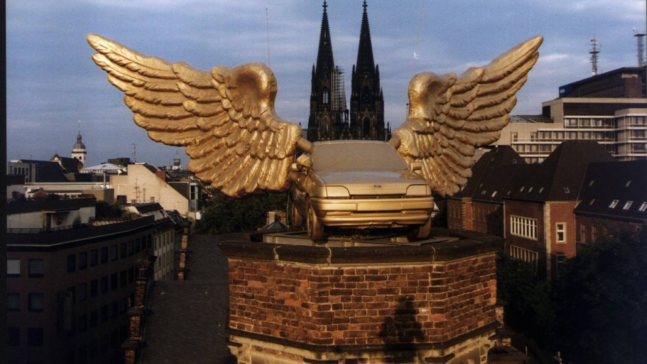 Ein goldenes Autos mit Flügeln steht auf einem Turm.