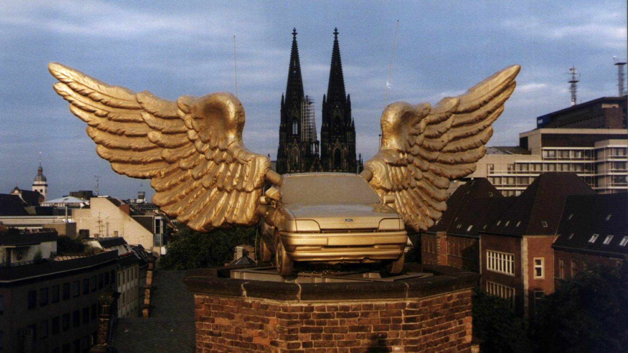 Ein goldenes Autos mit Flügeln steht auf einem Turm.