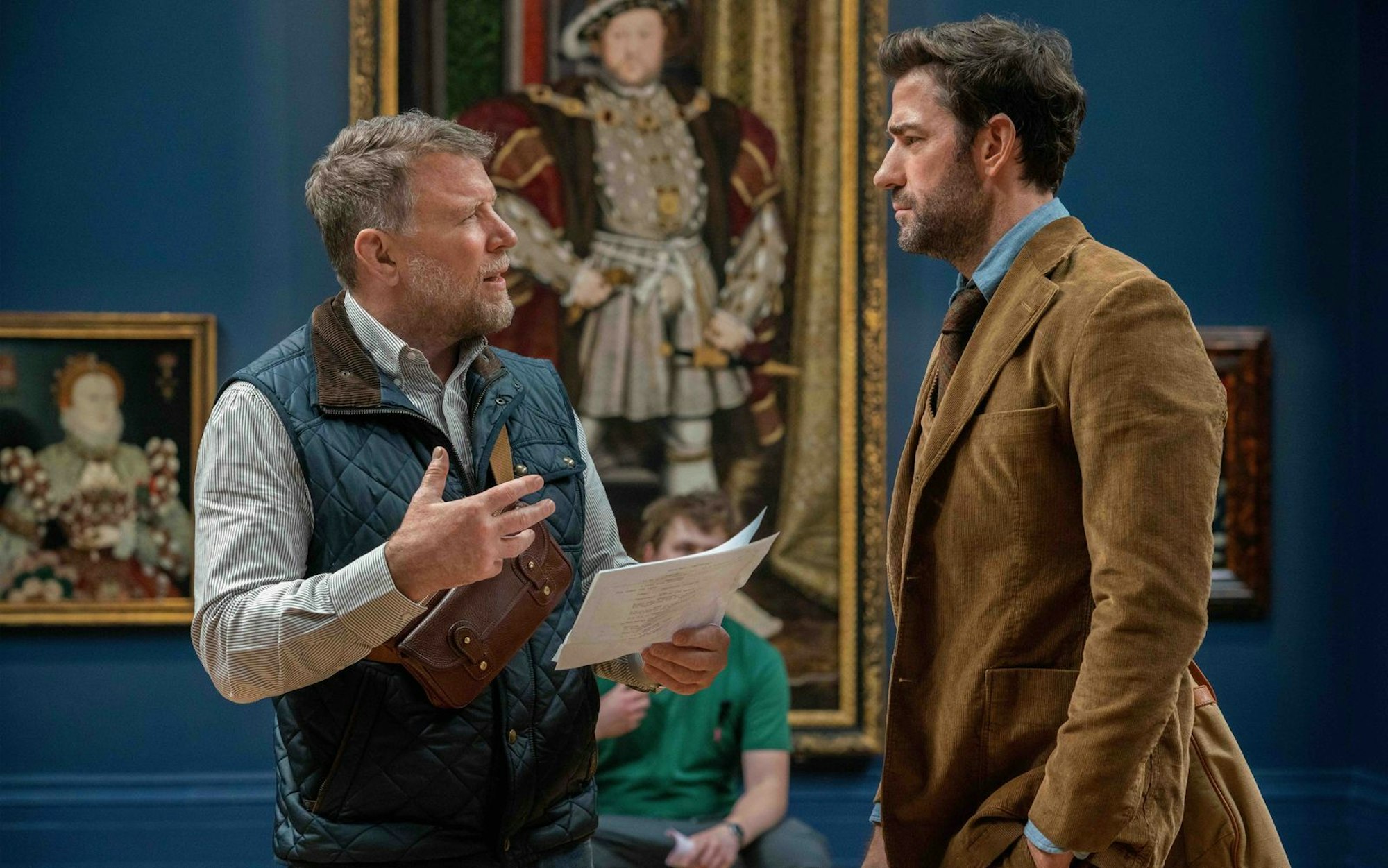 Behind the Scenes im Museum: Regisseur Guy Ritchie (links) erklärt seinem Hauptdarsteller John Krasinski eine Szene. (Bild: Apple TV+)