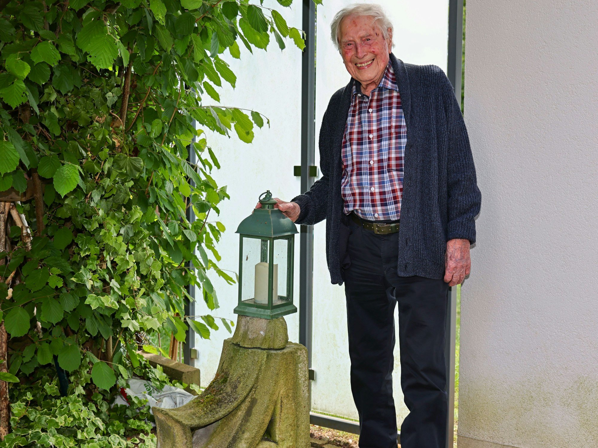 Ludwig Sebus neben einem Stück Kölner Dom in seinem Garten.