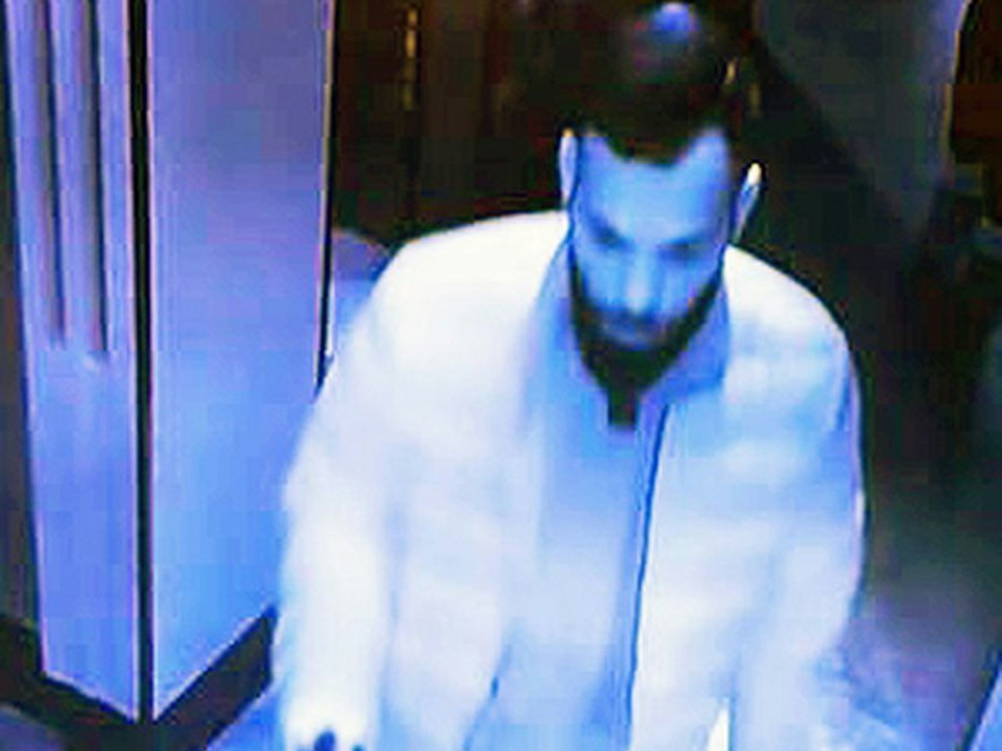 Ein Mann mit schwarzem Vollbart hält einen nicht erkennbaren Gegenstand in der Hand.