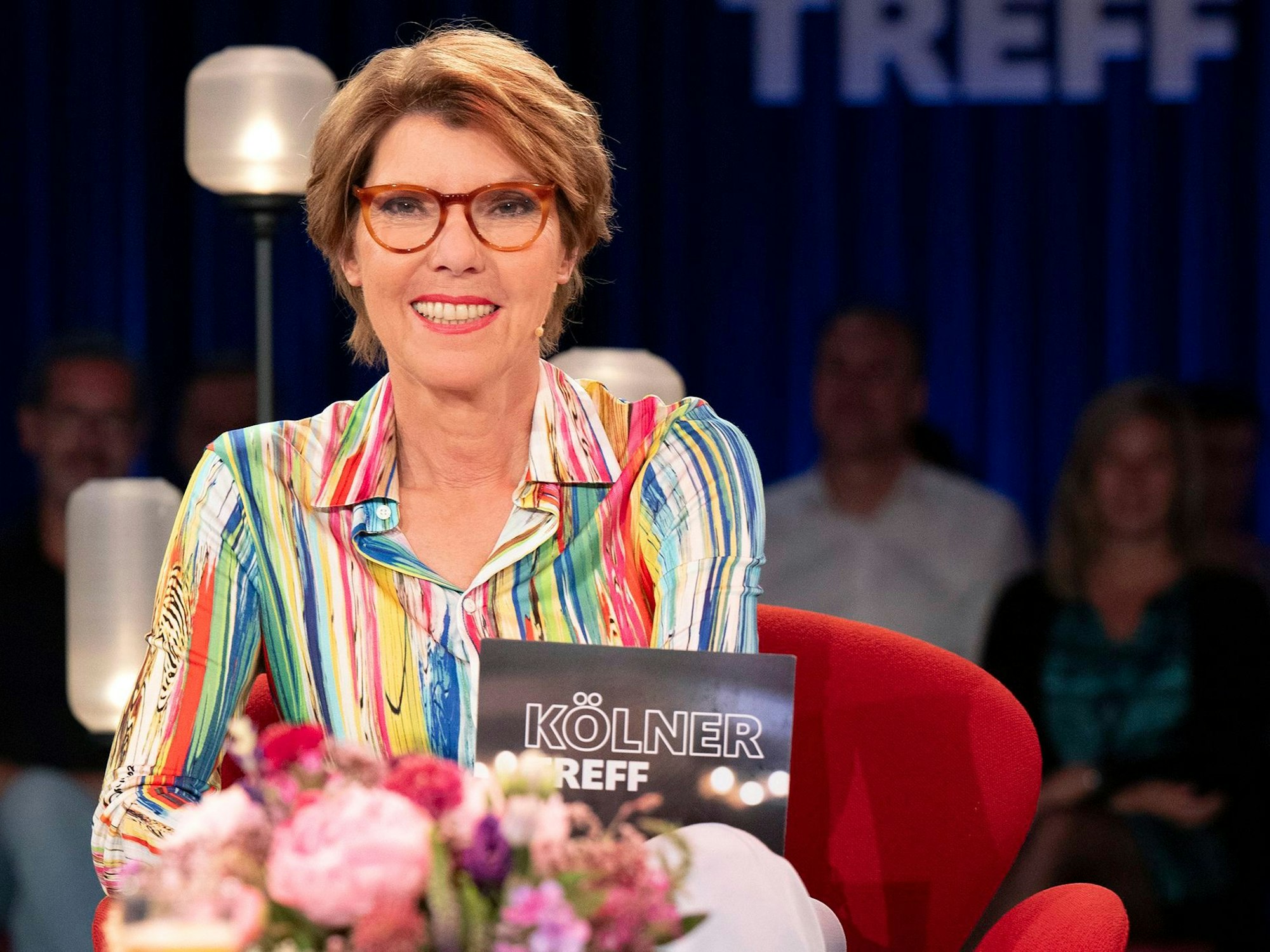 Eine Frau sitzt auf einem Sessel in einem TV-Studio.