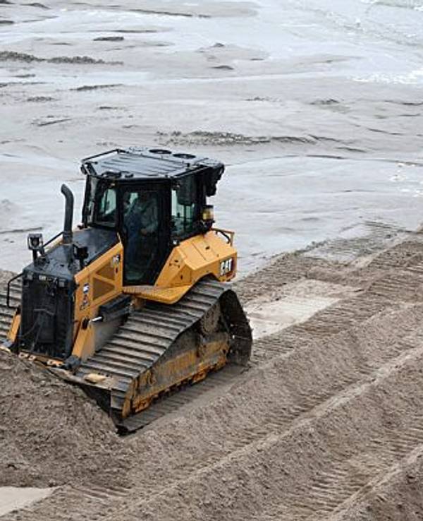 Eine Planierraupe verteilt im Dezember 2022 am Ostseestrand im Kreis Rostock Sand.