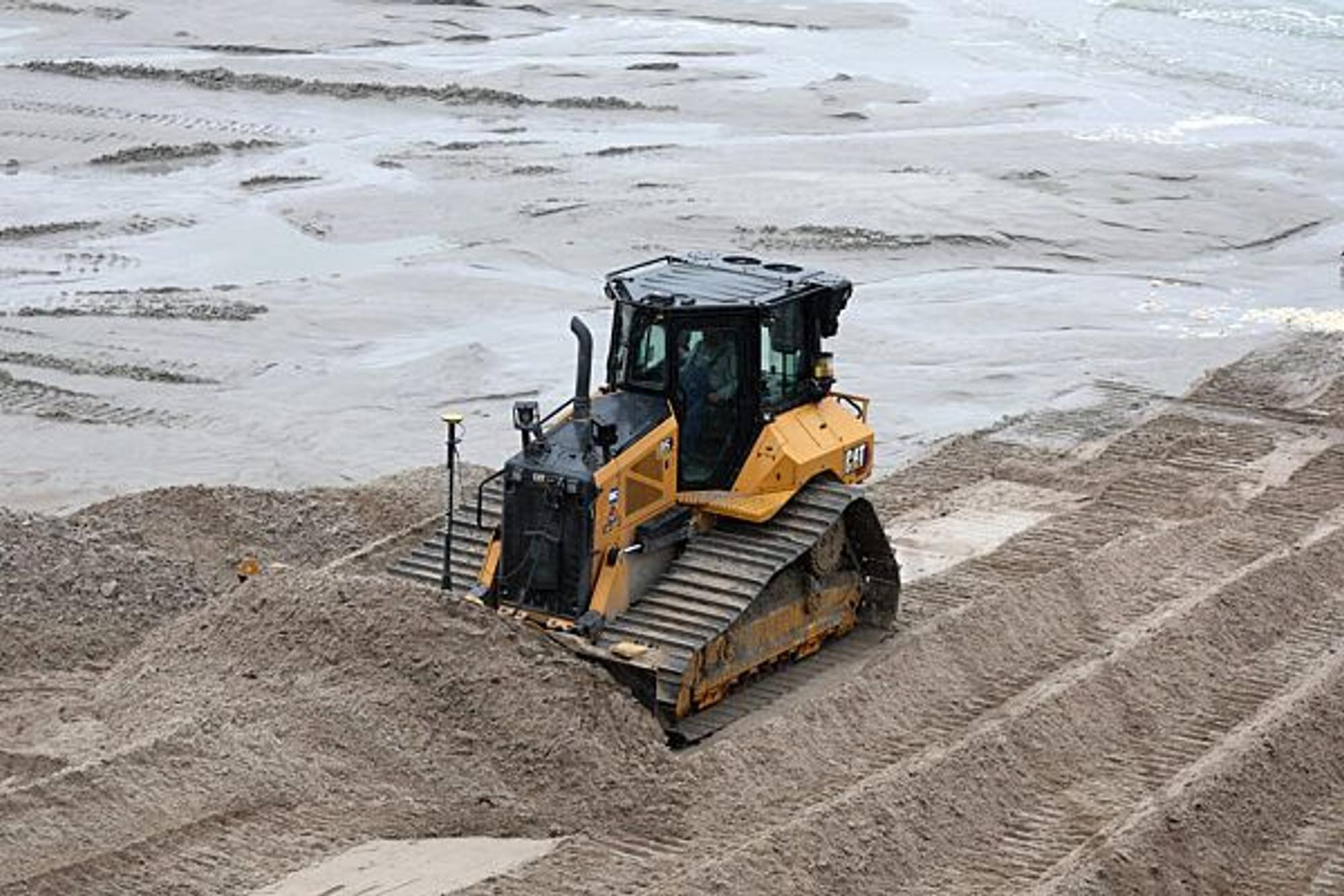 Eine Planierraupe verteilt im Dezember 2022 am Ostseestrand im Kreis Rostock Sand.