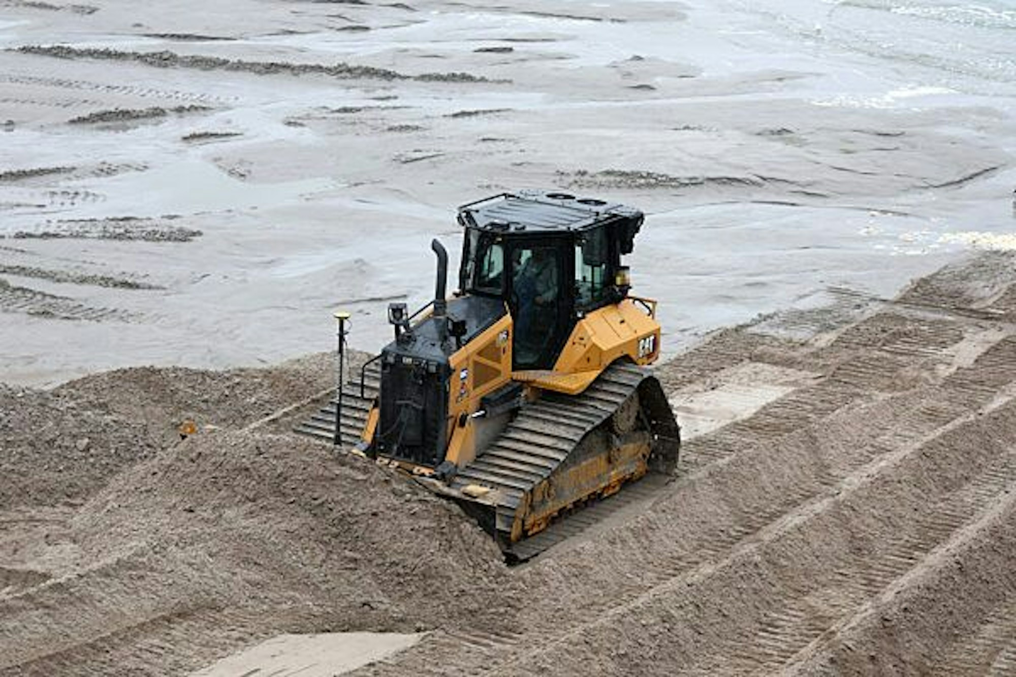 Eine Planierraupe verteilt im Dezember 2022 am Ostseestrand im Kreis Rostock Sand.