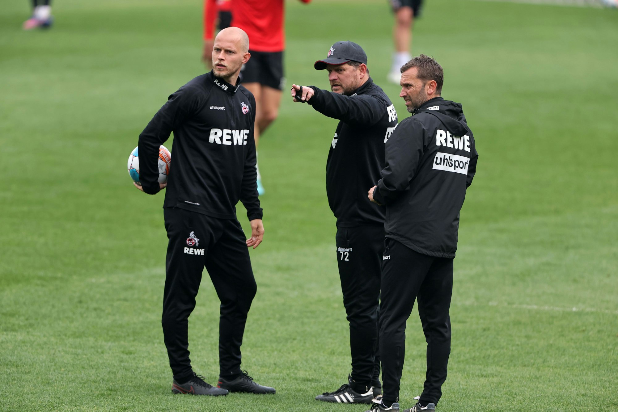 Steffen Baumgart zeigt seinen Co-Trainern etwas.