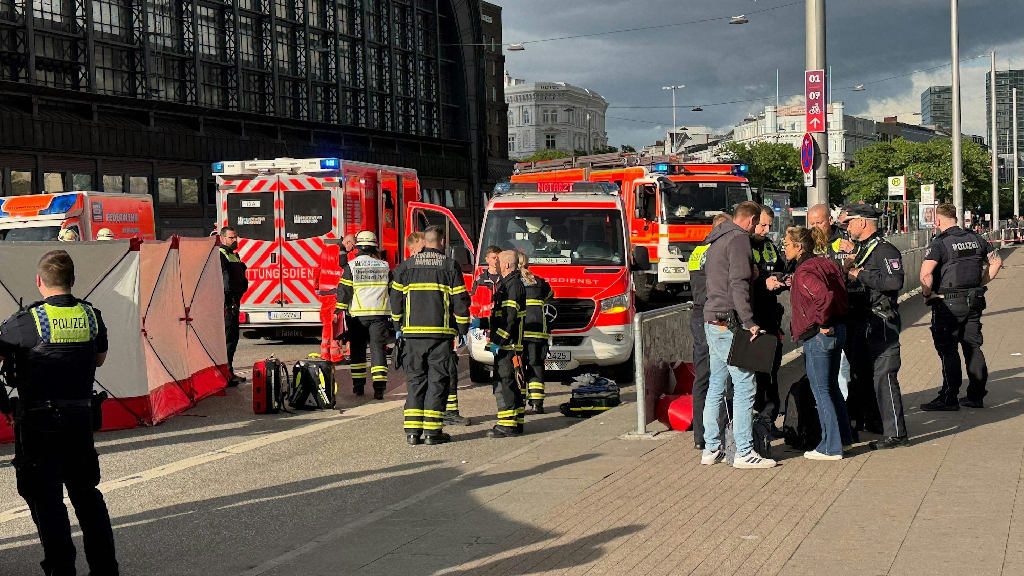 Nach der Messerattacke am Hamburger Hauptbahnhof stehen Einsatzkräfte von Rettungsdienst und Feuerwehr am 23. Mai 2025 vor dem Gebäude.