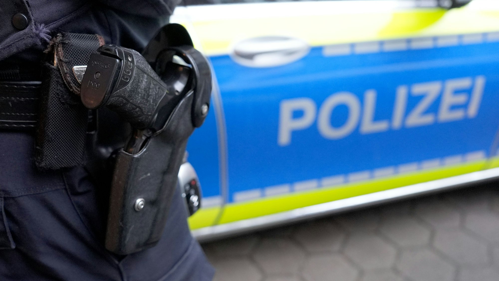 Ein Polizist steht vor einem Einsatzfahrzeug der Polizei.