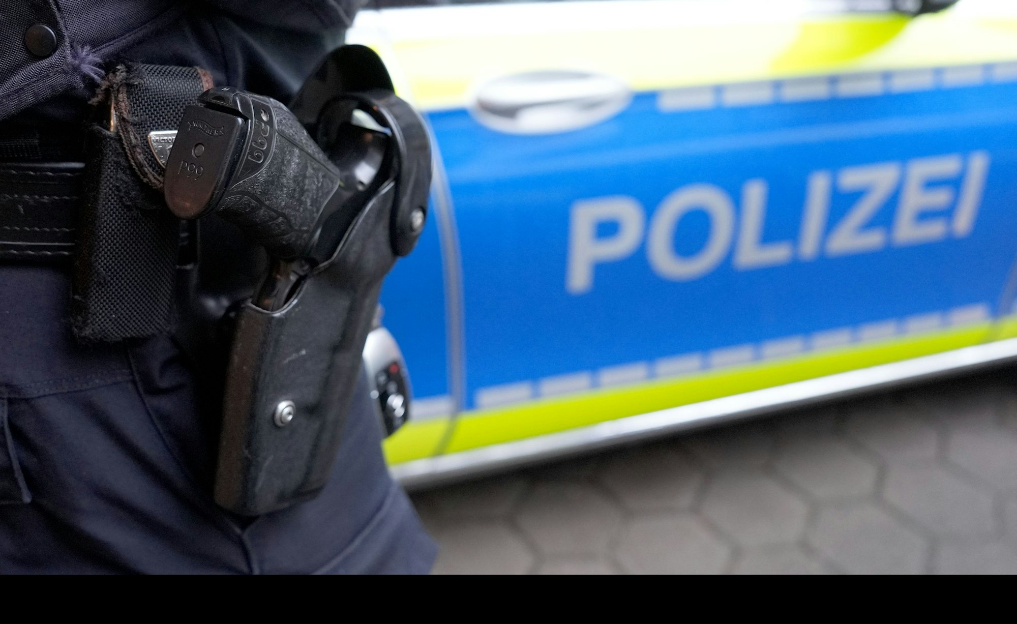 Ein Polizist steht vor einem Einsatzfahrzeug der Polizei.