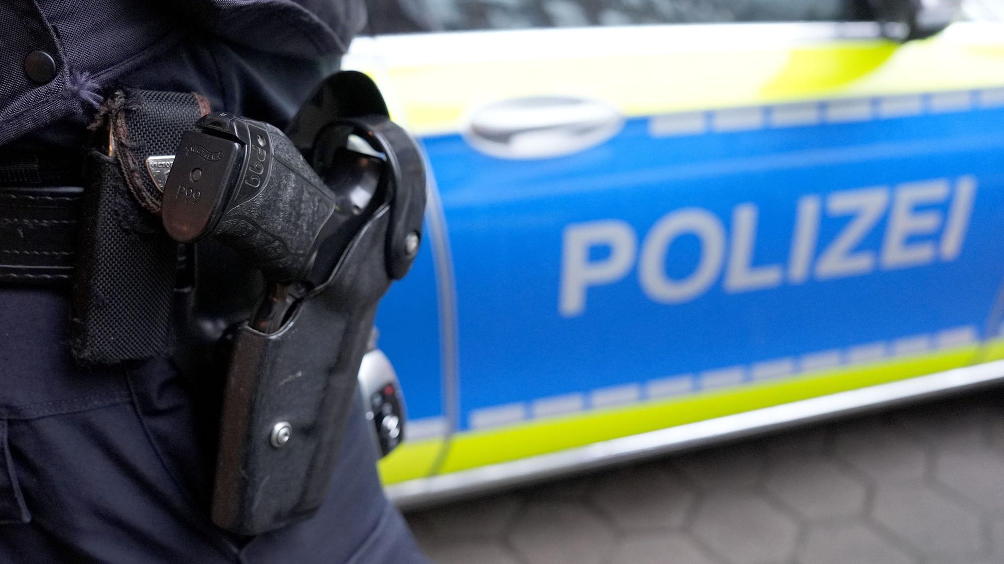 Ein Polizist steht vor einem Einsatzfahrzeug der Polizei.