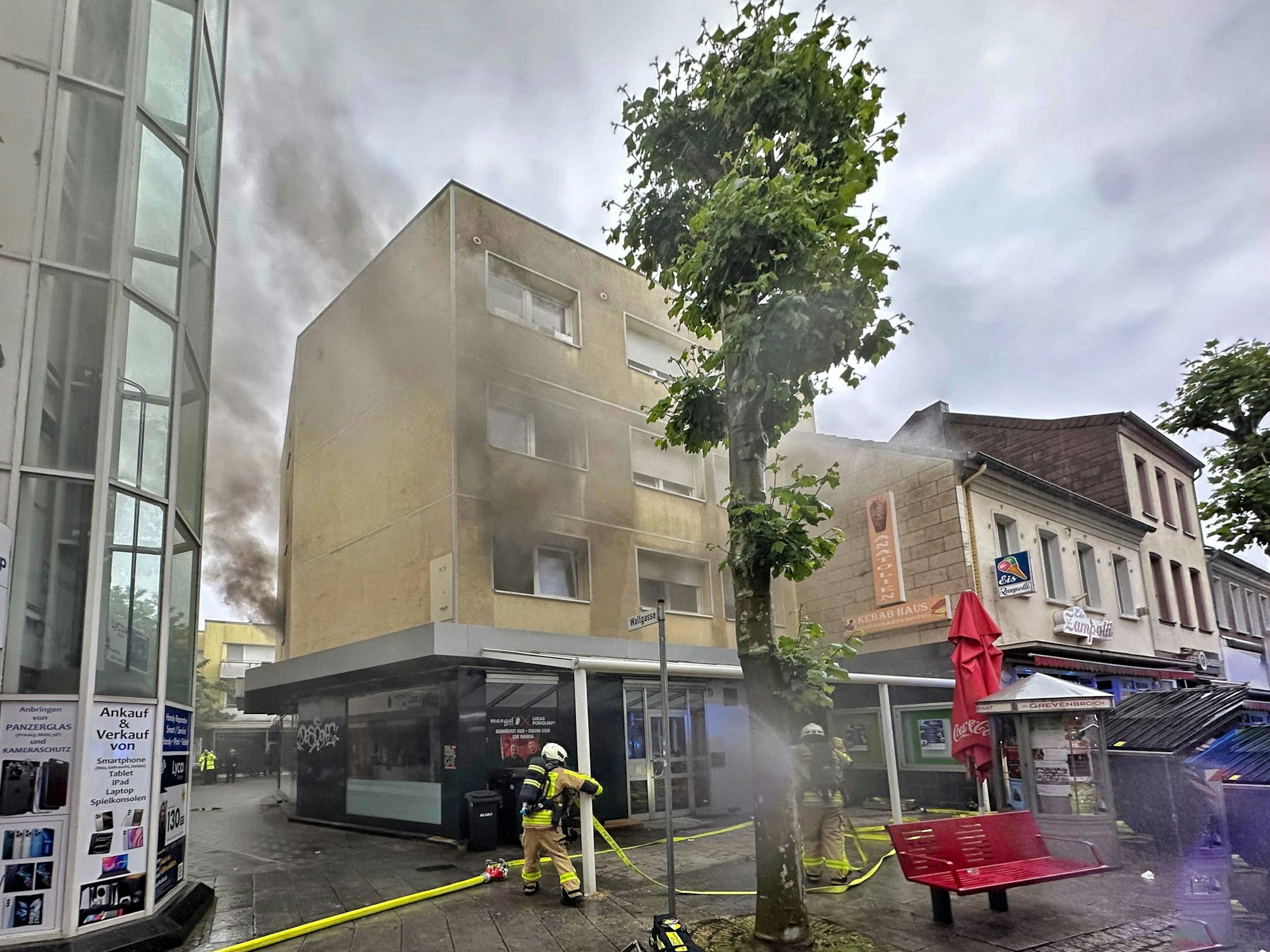 Feuerwehrleute stehen vor einem brennenden Haus.