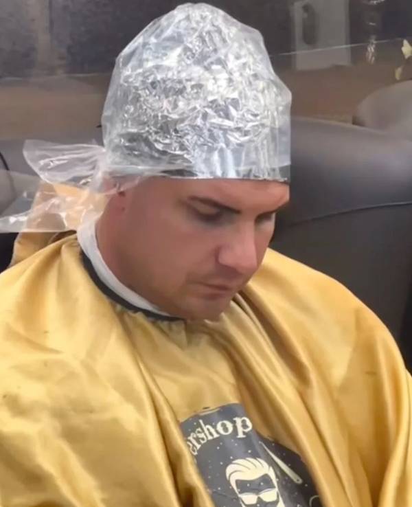 Ein Mann sitzt mit einer Alu-Haube beim Friseur.