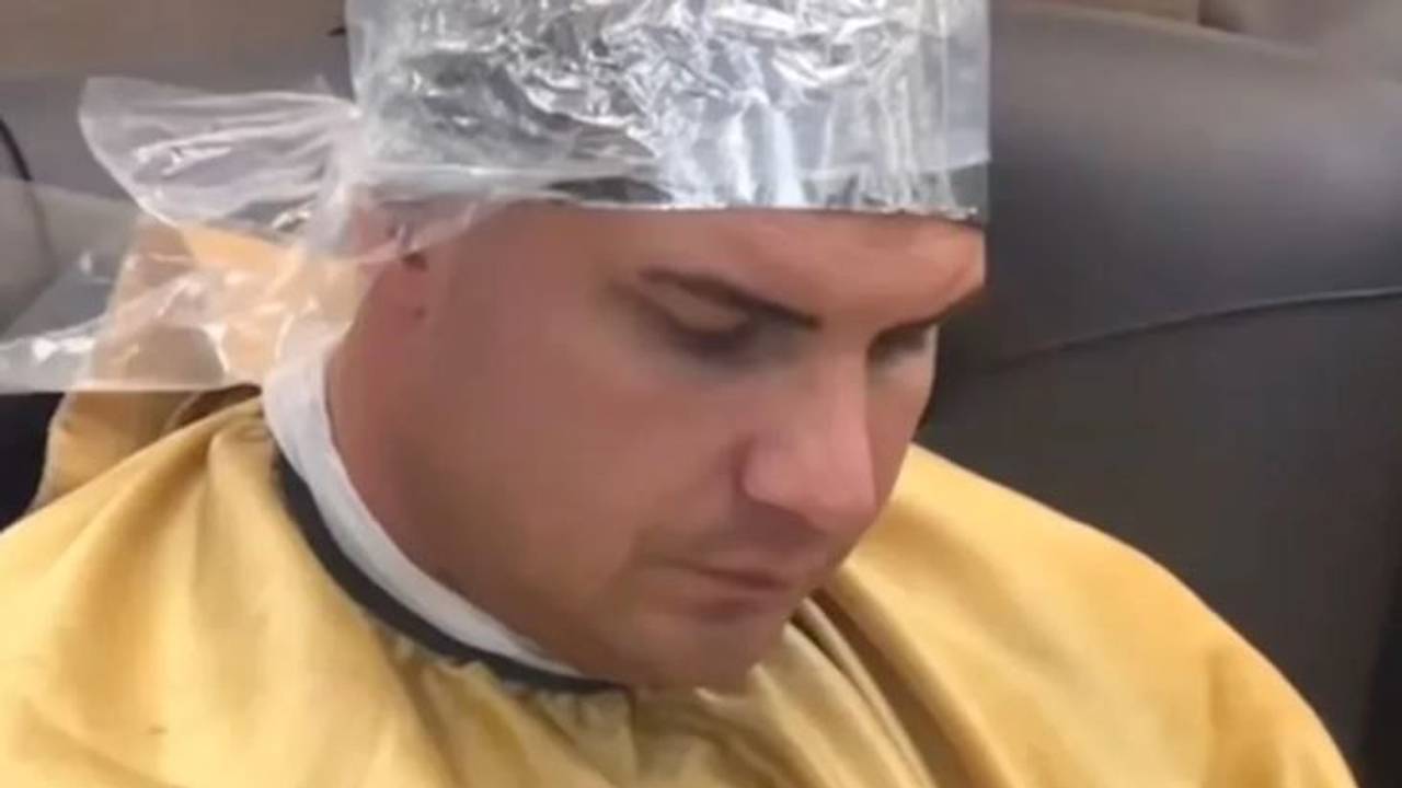 Ein Mann sitzt mit einer Alu-Haube beim Friseur.