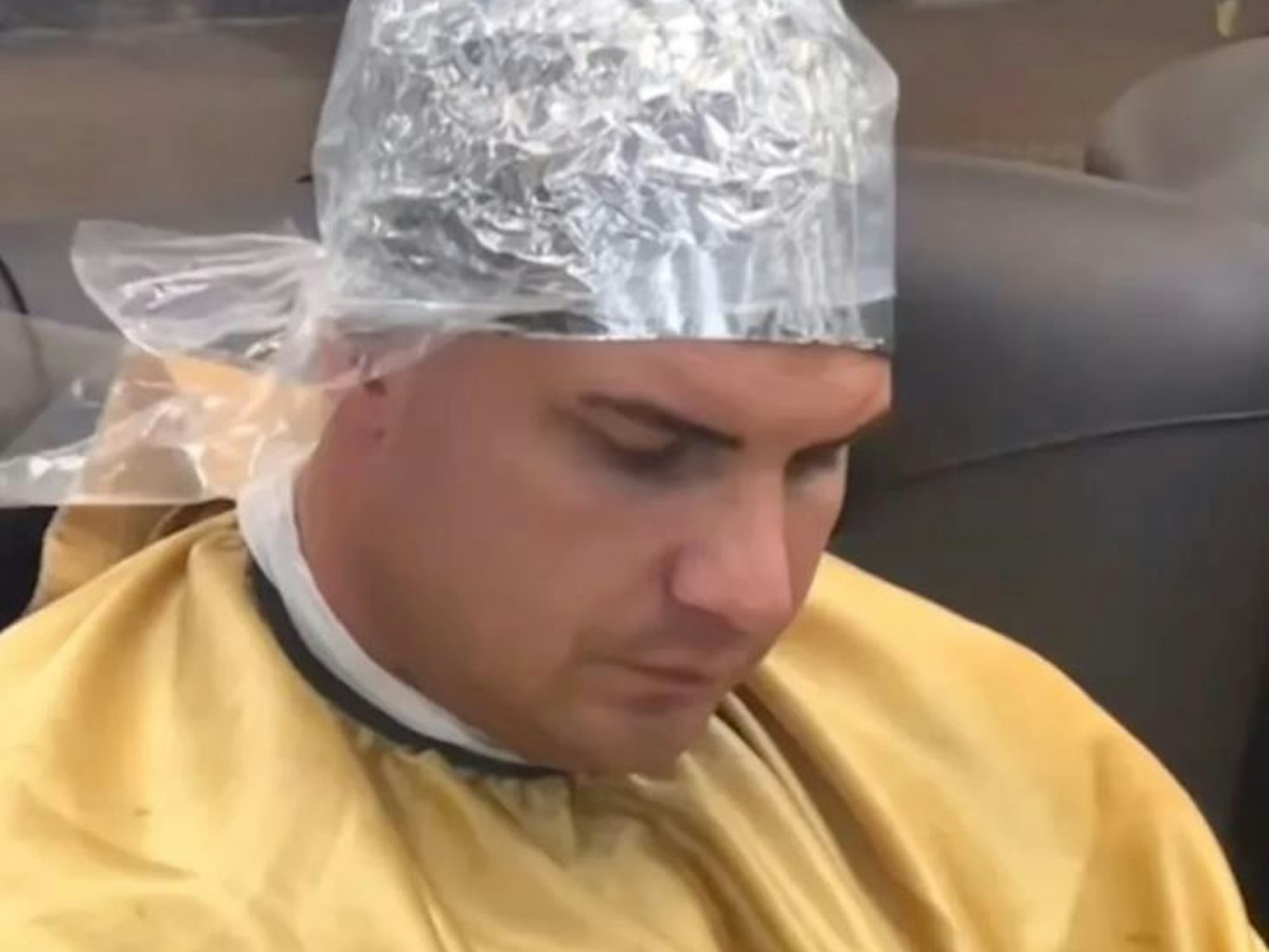 Ein Mann sitzt mit einer Alu-Haube beim Friseur.