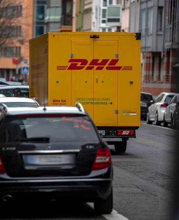 Ein DHL-Zustellfahrzeug steht in Köln auf der Straße.